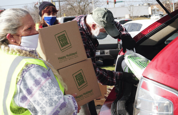 A volunteer loads a Family Food Box into a family's car. 