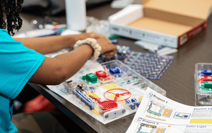 A teenage girl builds an engineering project, a part of the Light the Spark Kit she received.