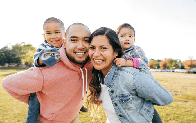 Immigrant family of four, a couple holds up their two children.