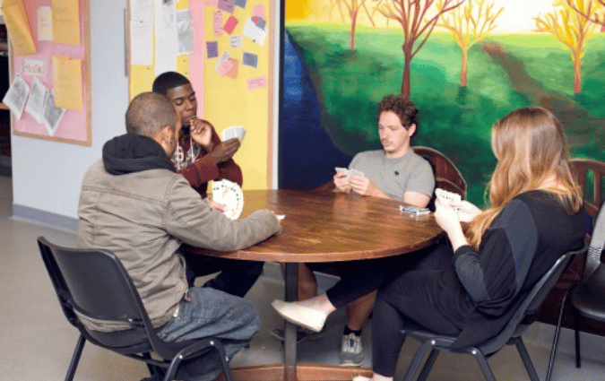 Teens at a youth center playing cards together.