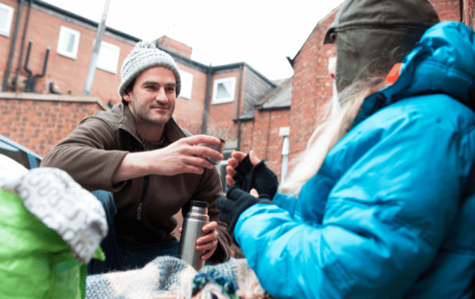 A volunteer reaches out to an individual experiencing homelessness.